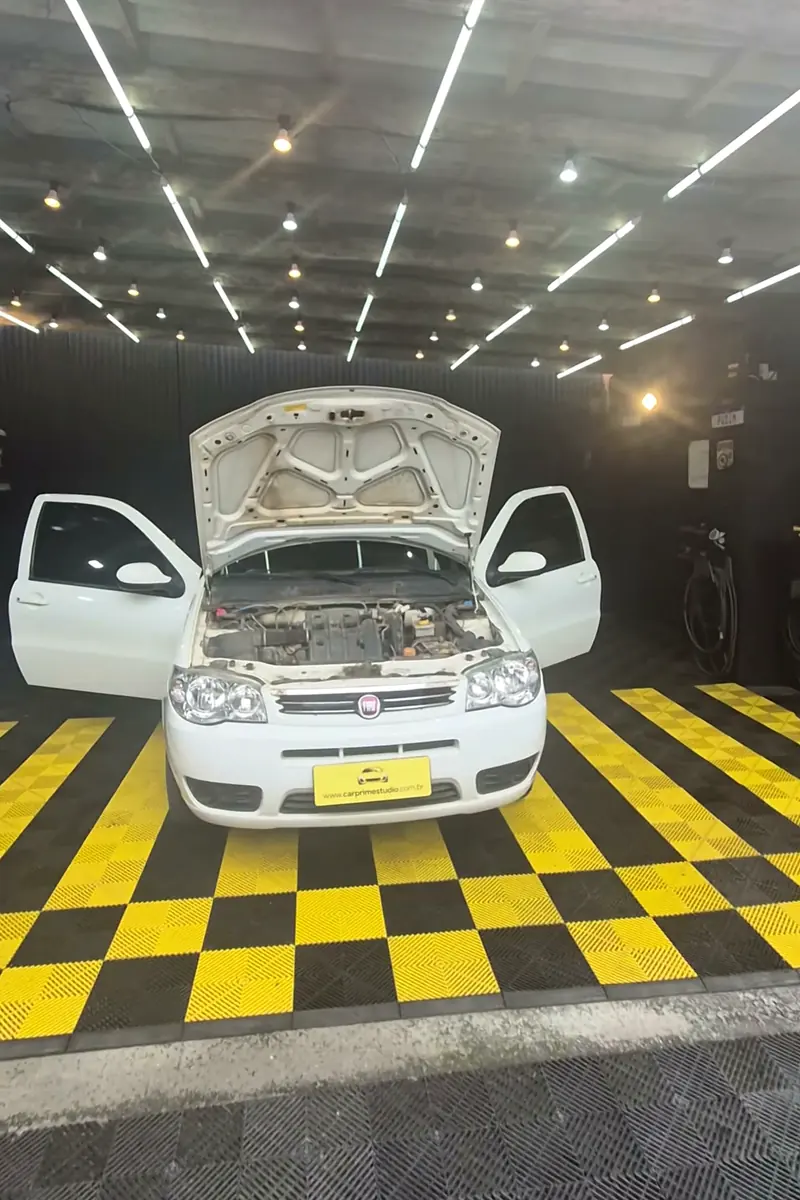 Fiat Palio branco no tablado amarelo e preto, durante a transformação