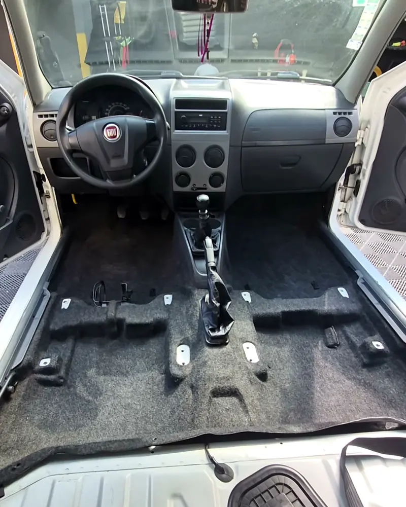 Interior do carro desmontado, sem bancos e com o assoalho exposto para a limpeza